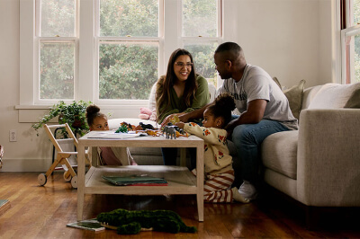 Family sits around coffee table in their living room covered in dinosaurs and discuss the Fed rate cuts.